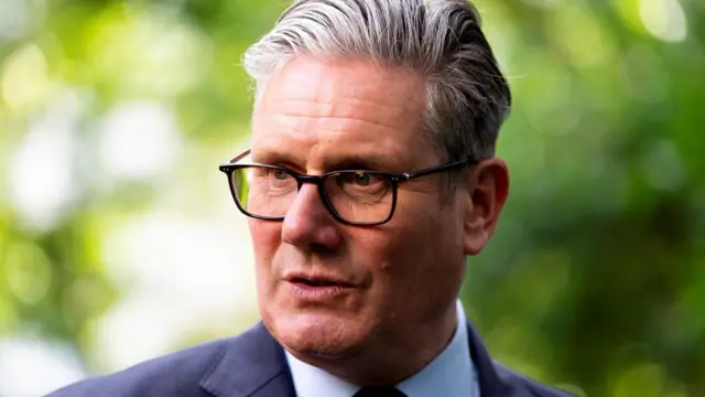Sir Keir Starmer is pictured wearing glasses, a navy jacket and white shirt.