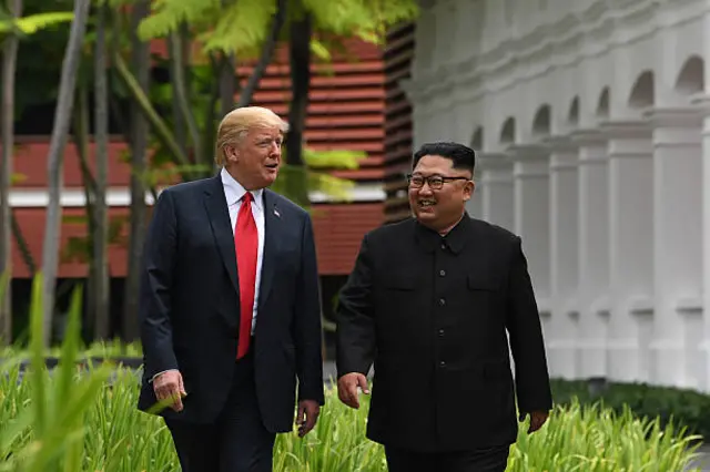 North Korea's leader Kim Jong Un (R) walks with US President Donald Trump (L) during a break in talks at their historic US-North Korea summit
