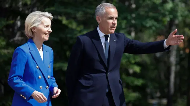European Union President Ursula von der Leyen, wearing a blue jacket, smiles and talks to Carney.