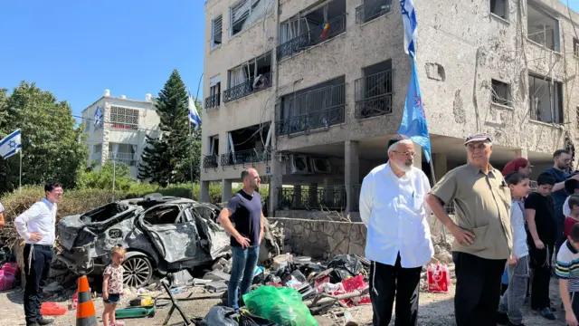People stand outside the wreckage of a building in Haifa, Israel.