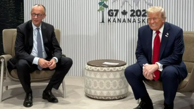 Trump and Merz sit together with a white wall reading "G7 2025 Kananaskis"
