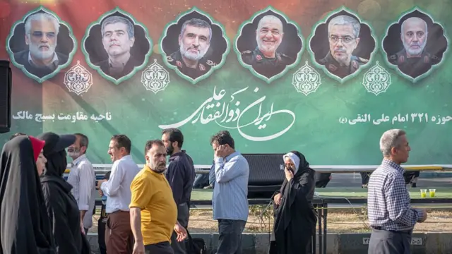 People walk past portraits of slain Iranian generals in Tehran.