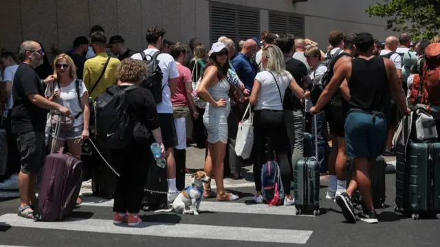 People with suitcases stand and wait