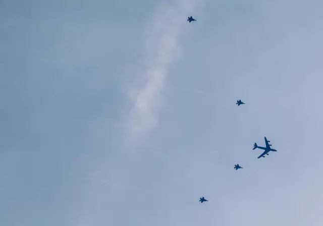 At least four F-35 fighter jets flanked by an air refuelling tanker plane.