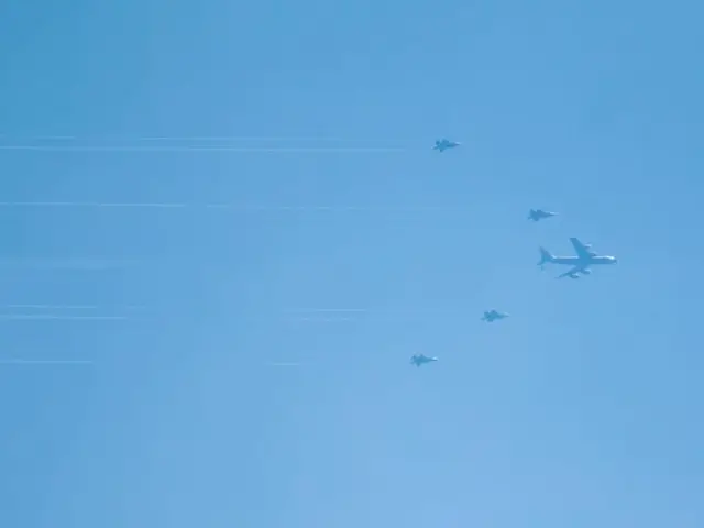 At least four F-35 fighter jets flanked by an air refuelling tanker plane.