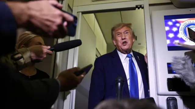 Donald Trump speaks to reporters while travelling on board Air Force One