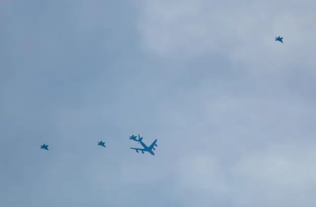 At least four F-35 fighter jets flanked by an air refuelling tanker plane.