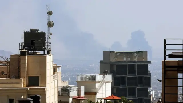 Smoke is rising behind tall buildings
