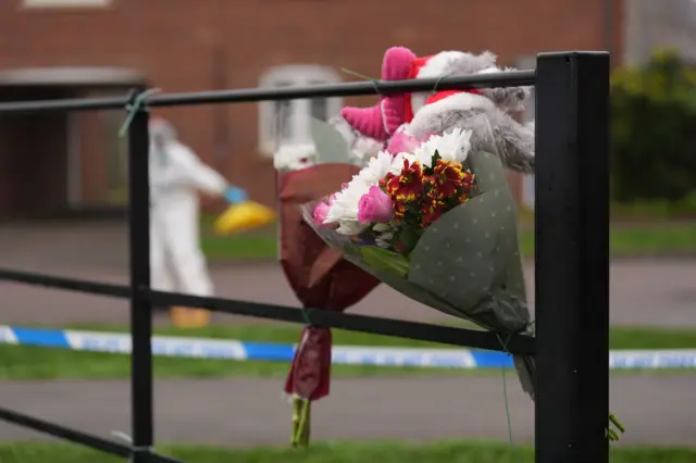 Floral tributes are left at the scene near an apartment block on Santa Cruz Avenue in Newton Leys, near Bletchley.