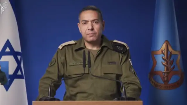 Effie Defrin, wearing a khaki military uniform, speaks at a lectern