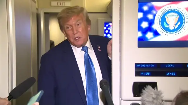 Donald Trump speaks to reporters on board Air Force One