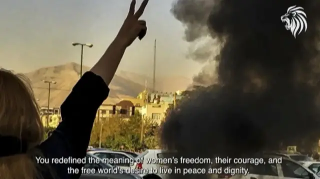 Image of woman's arm up in the air with smoke coming out of a white car