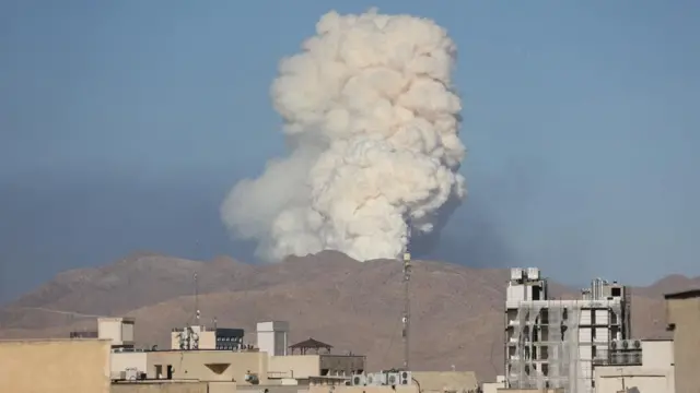 Smoke rises from the site of a strike behind hills outside Tehran