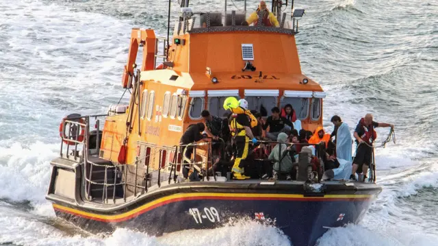 Rescue personnel bring migrants ashore, after a boat carrying migrants from France sunk in the English Channel.