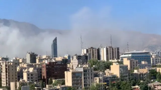 Grey smoke can be seen against the mountains following new Israeli air raids over Tehran