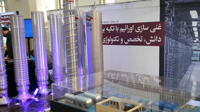 Long silver centrifuges glow in ultraviolet purple above a display case showing several electrical components.