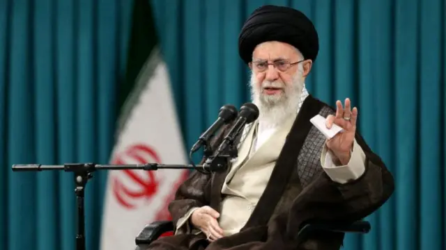 Iran's Supreme Leader Ayatollah Ali Khamenei speaks during a meeting with a group of students in Tehran. he wears a black turban and black robes. he speaks into two microphones. with one hand he gesutres and is holding note cards.