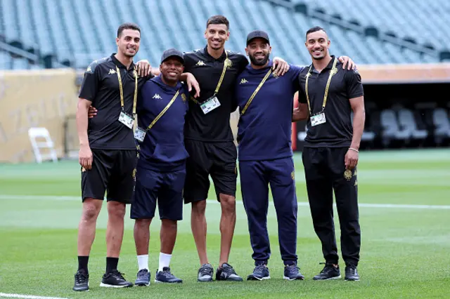Youssef El Motie, Omar Aqzdaou, and El Mehdi Benabid of Wydad AC pose for a photo with staff on the pitch ahead