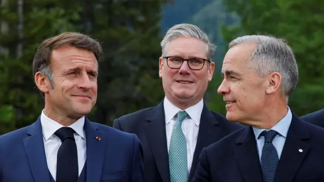 France's President Emmanuel Macron, Canadian Prime Minister Mark Carney and British Prime Minister Keir Starmer speak as they pose for a photo during the G7 Leaders' Summit.