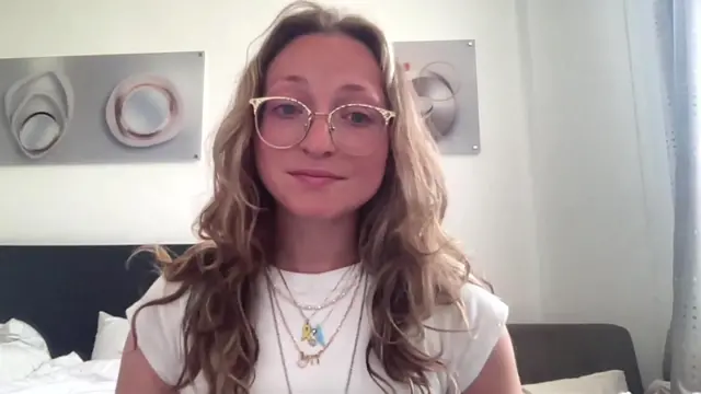 Naomi Brookarsh in a white t-shirt, necklaces and glasses
