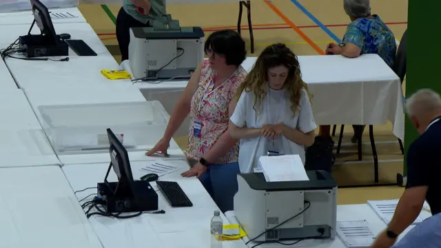People in the counting hall. The picture shows scanning equipment and computers.