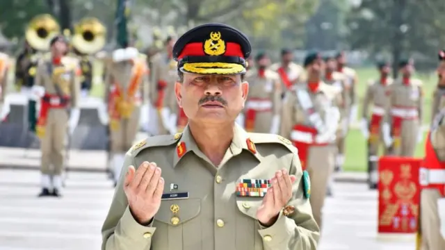 Pakistan's Army Chief General Asim Munir in army dress praying at a monument to honor soldiers who lost their lives in line of duty