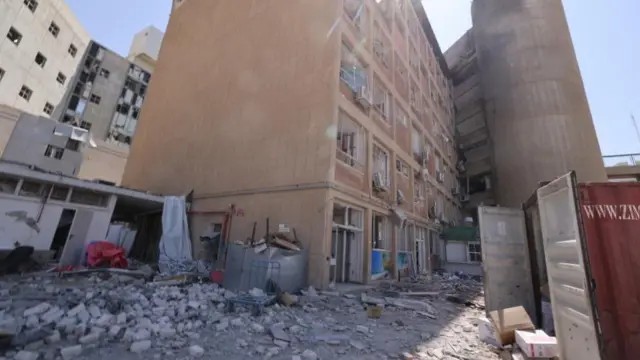 A damaged building with rubble on the street.