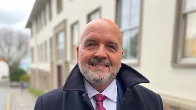 Man wearing a shirt, tie, jacket and coat