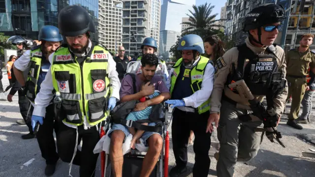 Emergency personnel assist a man and a child following a strike from Iran on Israel, in Ramat Gan, Israel.