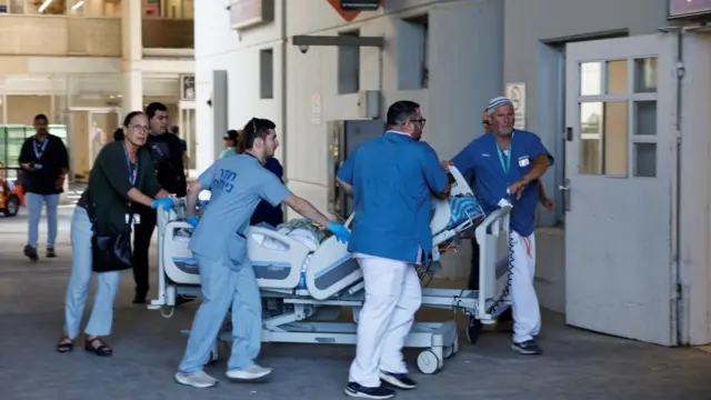 Medical staff in blue outfits running, pushing a medical bed on wheels.