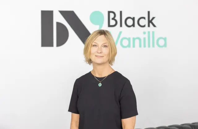 Nichole Culverwell in a black top. Stood in front of a white background