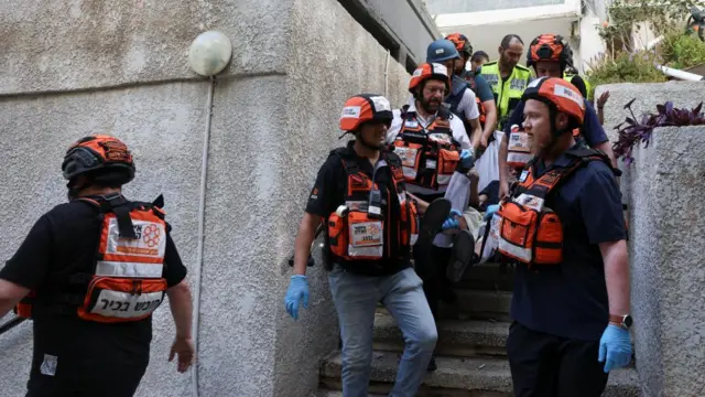 Emergency personnel assist a person following a strike from Iran on Israel