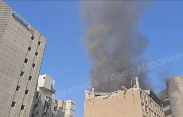 Still from a video of the Soroka Hospital's exterior that shows smoke rising out of its roof, which appears to have partially caved in.