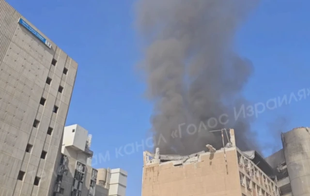 A building with smoke rising from it and damage to the top.