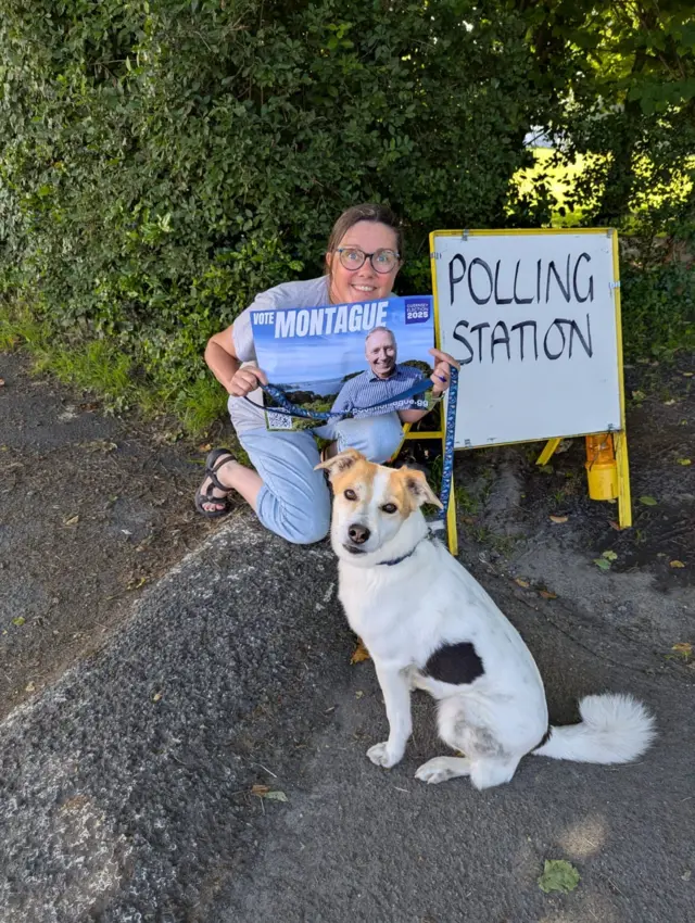 Connie Armstrong crouched by a polling station with her dog
