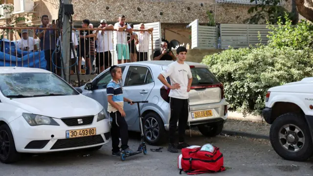 Onlookers gather at an impact site following a missile strike from Iran on Holon