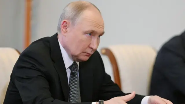 Putin sits as he takes questions on the sidelines of the 28th Saint Petersburg International Economic Forum