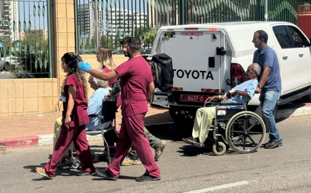 People in medical uniforms transporting patients in wheelchairs