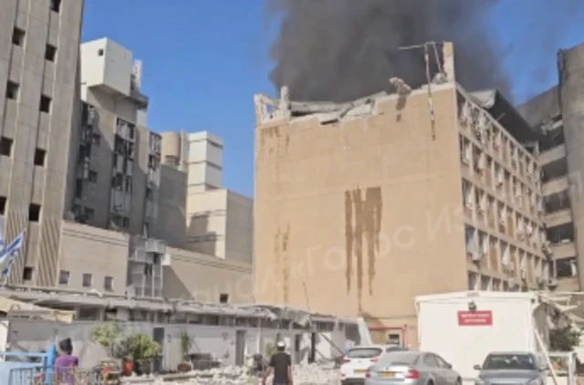Still from a video of the Soroka Hospital's exterior that shows smoke rising out of its roof, which appears to have partially caved in.