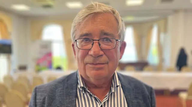 Man in striped shirt and grey jacket
