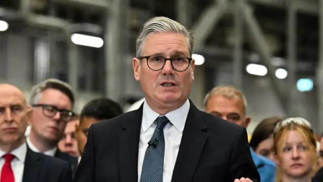 Headshot of Starmer speaking as people stand behind him
