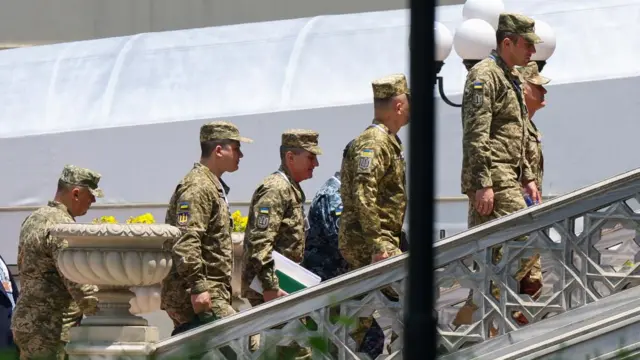 Several members of the Ukrainian delegation wearing military uniform walking up the stairs outside the Ciragan Palace in Istanbul.