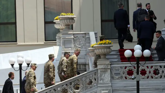 A group of men in military uniform walk up a set of stairs