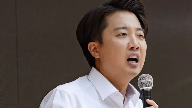 Lee Jun-seok, dressed in a white-collared shirt, holds a microphone as he appeals for public support at Gyeongui Line Forest Park in Seoul on 30 May