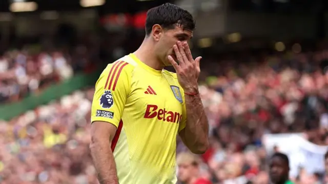 Emiliano Martinez of Aston Villa leaves the pitch after being shown a red card for a foul on Rasmus Hojlund of Manchester United