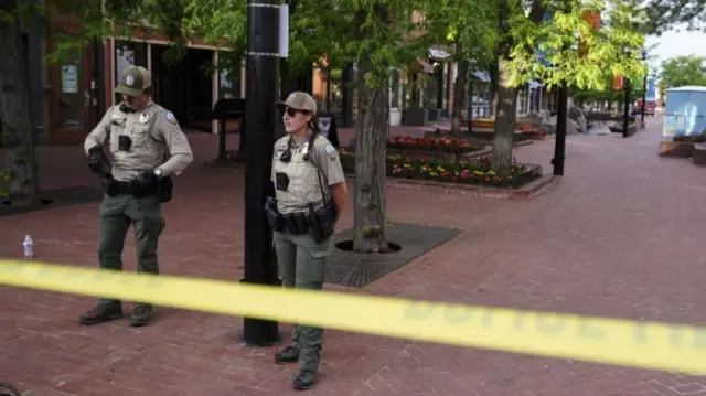 Two police officers stand guard behind a police cordon at a pedestrian mall