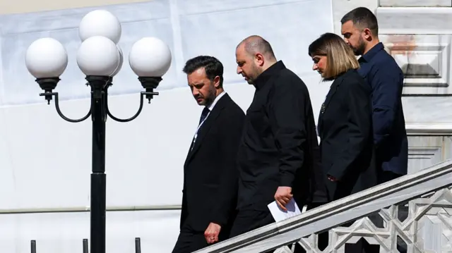 Ukrainian Defence Minister Rustem Umerov walks with other delegates down a set of stairs