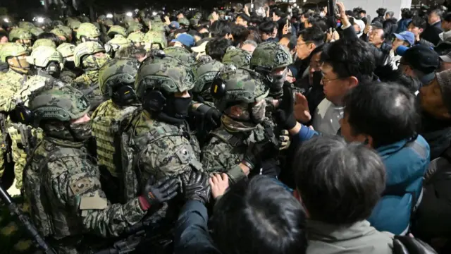 Soldiers try to enter the National Assembly building in Seoul in the early hous on 4 December, 2024