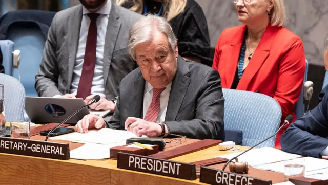 António Guterres sits behind a microphone behind a desk in the Security Council.