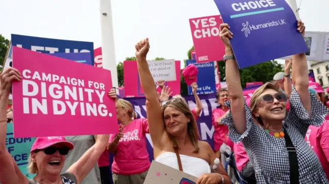 Assisted dying bill supporters celebrate holding placards reading campaign for dignity in dying